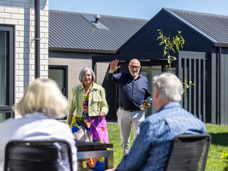 Man and lady walking toward a group of older adults, waving